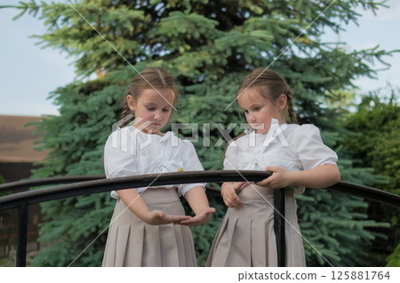 Twins are focused on a little forest guest. Their hairstyles and outfits create a sense of purity and unity. Twins are focused on a little forest guest. Their hairstyles and outfits create a sense of purity and unity. 125881764