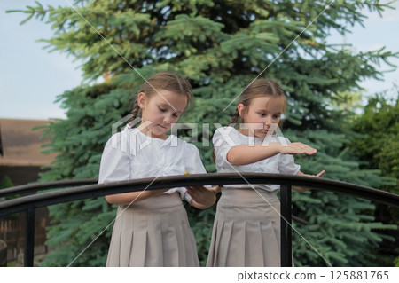Two little sisters stand side by side, completely absorbed in the moment. Each braid mirrors the other. Two little sisters stand side by side, completely absorbed in the moment. Each braid mirrors the other. 125881765