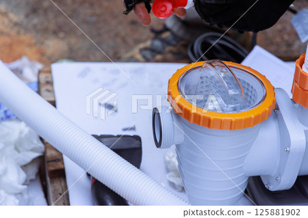 Worker prepares components of water swimming pool pump, handling parts at construction site 125881902