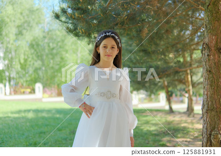 The photo shows a girl on the eve of her First Communion in a long dress. A little lady in a white dress.  125881931
