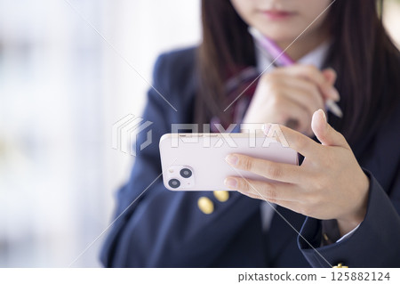 女高中生用智慧型手機學習的手 女高中生用智慧型手機學習的手 125882124