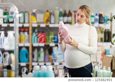 Interested pregnant woman choosing safe laundry detergent in store Interested pregnant woman choosing safe laundry detergent in store 125882401