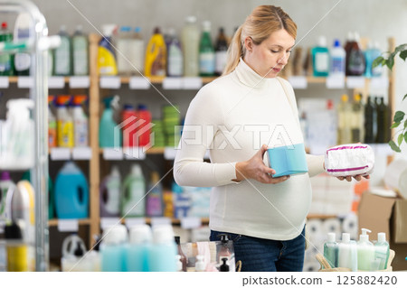 Thoughtful pregnant customer choosing feminine pads in hygiene store Thoughtful pregnant customer choosing feminine pads in hygiene store 125882420