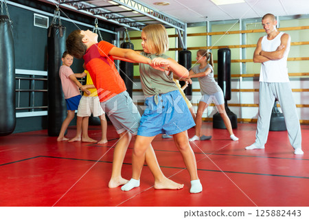 Kids exercising self-protection moves in gym Kids exercising self-protection moves in gym 125882443