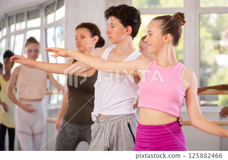 Teenage girl practicing ballet positions in pair with boy in dance studio 125882466