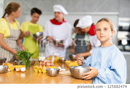 Interested tween girl attending group culinary classes for children Interested tween girl attending group culinary classes for children 125882474