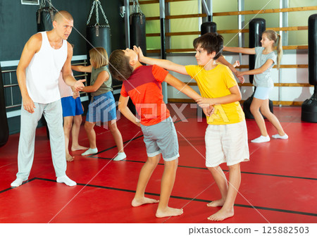 Children practicing self defence technique in pairs 125882503