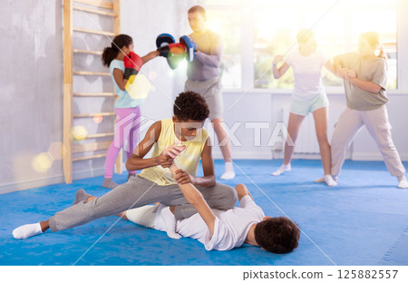 African teenager applying armlock in mock fight with boy at self-defense classes African teenager applying armlock in mock fight with boy at self-defense classes 125882557