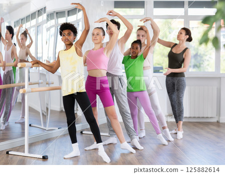 Teenage boys and girls practicing battement tendu position of ballet in dancehall 125882614