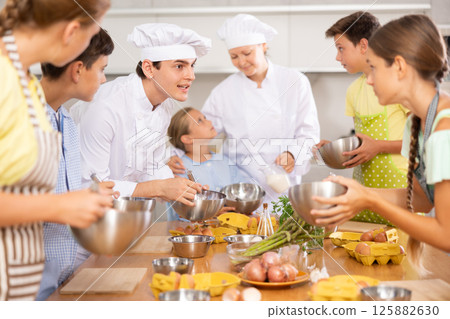 Young chef giving culinary classes to group of interested tweens Young chef giving culinary classes to group of interested tweens 125882630
