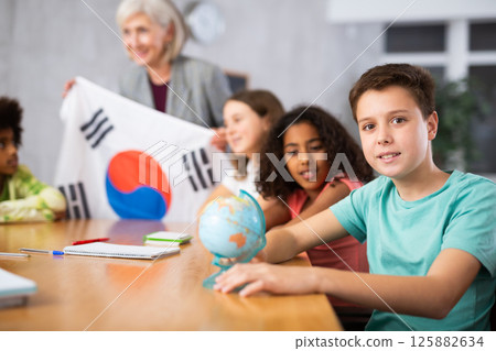 Female teacher showing south korean flag to kids in geography class 125882634