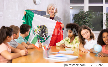 Friendly woman teacher tells pupils the history of Mexico 125882650