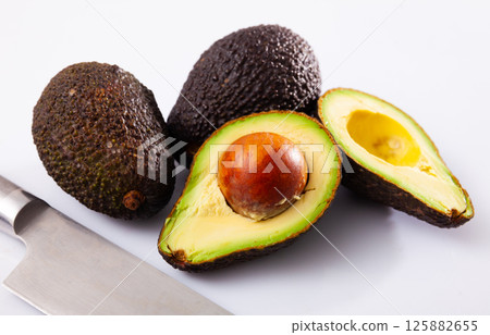 Avocadoes and kitchen knife on white background Avocadoes and kitchen knife on white background 125882655