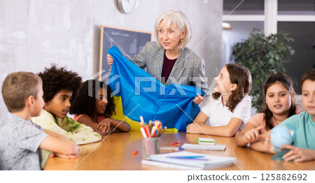 students listen to woman teacher who talks about Ukraine 125882692