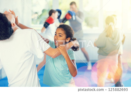 Preteen children pairs learning strength self-defense in gym Preteen children pairs learning strength self-defense in gym 125882693