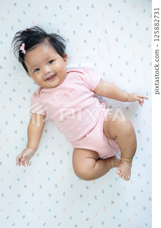 Happy newborn baby girl asian heritage indoor portrait playful environment close-up view 125882731