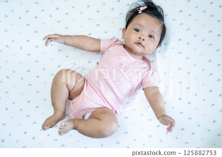 Newborn asian baby in playful pose home setting cozy environment close-up perspective Newborn asian baby in playful pose home setting cozy environment close-up perspective 125882753