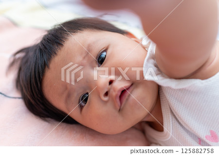 Newborn asian baby exploring her world cozy home candid image indoor close-up moment Newborn asian baby exploring her world cozy home candid image indoor close-up moment 125882758