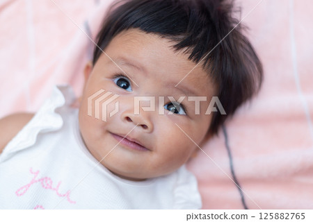 Newborn asian baby smiling in cozy indoor setting captivating portrait focused innocence 125882765
