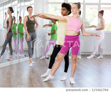 Teenage girl practicing ballet positions in pair with boy in dance studio 125882769