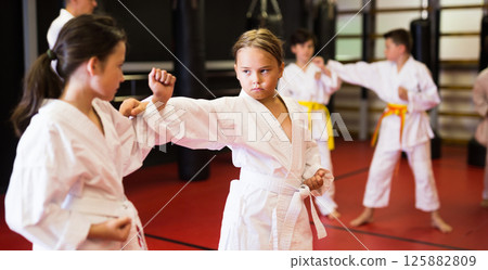 Girls fighting in pair to use new karate techniques during class 125882809