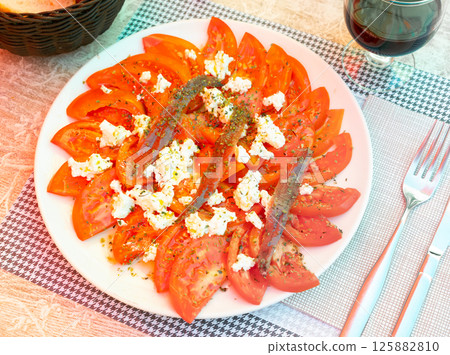 Tasty tomato slices with cheese and anchovies. Tasty tomato slices with cheese and anchovies. 125882810
