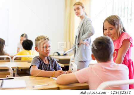 Concentrated preteen girls and boys solving teacher assignments in groups 125882827