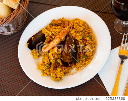 Spanish rice dish paella tinted with saffron. Prepared with olive oil and seafood 125882868