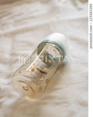 Feeding time for babies transparent baby bottle soft surface lifestyle setting close-up viewpoint Feeding time for babies transparent baby bottle soft surface lifestyle setting close-up viewpoint 125883260