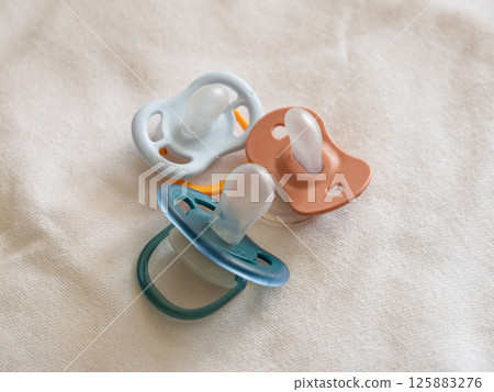 Baby pacifiers soft fabric nursery setting still life calm vibe close-up infant care 125883276