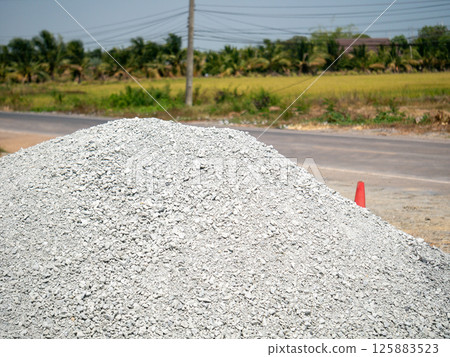 Construction material pile rural roadside gravel green landscape ground level industrial scene 125883523