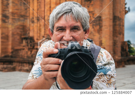 happy old man tourist traveling photographer with a camera takes pictures of landmarks at the ancient Po Nagar Cham Towers in Nha Trang in Vietnam in Asia happy old man tourist traveling photographer with a camera takes pictures of landmarks at the ancient Po Nagar Cham Towers in Nha Trang in Vietnam in Asia 125884007