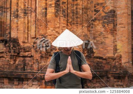 man in Vietnamese cone hat non la prays at Po Nagar Cham Towers in Nha Trang, Vietnam. Concept of travel in Asia 125884008