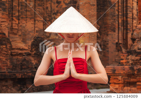 female tourist in a Vietnamese hat Non La prays at Po Nagar Cham Towers in Nha Trang in Vietnam in Asia female tourist in a Vietnamese hat Non La prays at Po Nagar Cham Towers in Nha Trang in Vietnam in Asia 125884009