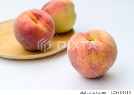 Peaches fruit on wooden plate with white background 125884110
