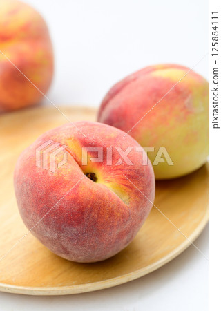 Peaches fruit on wooden plate with white background Peaches fruit on wooden plate with white background 125884111
