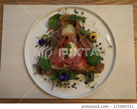 Prosciutto and egg galette decorated with flowers and sprouts Prosciutto and egg galette decorated with flowers and sprouts 125884331