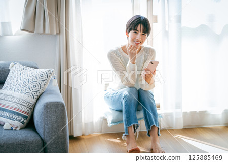 A woman who operates a smartphone in the room 125885469