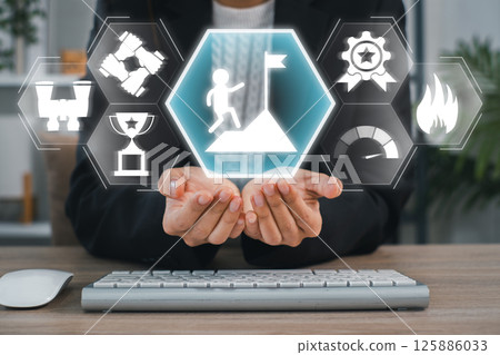 Businessman holding digital icons symbolizing goal achievement and success in a futuristic interface. Businessman holding digital icons symbolizing goal achievement and success in a futuristic interface. 125886033