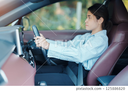 Businesswoman driver driving a car on the road, hand controlling steering wheel in electric modern automobile. Journey, trip and safety Transportation concepts 125886820