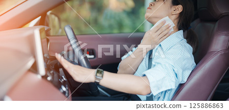 woman driving car with broken air conditioner in hot summer weather, uses tissue paper napkin to wipe the sweat off her forehead. Businesswoman driver is tired, Exhausted overheated and stressed 125886863