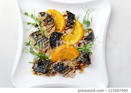 Grilled mackerel fish oranges and rosemary served on a stylish plate. 125887400