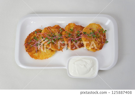 Crunchy potato pancakes with sour cream and fresh chives served in an iron frying pan 125887408