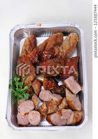 delivery in disposable containers mixed grilled meat platter. Beef, pork, poultry, sausages, grilled garlic, chili pepper, red tomatoes on wooden rustic background. delivery in disposable containers mixed grilled meat platter. Beef, pork, poultry, sausages, grilled garlic, chili pepper, red tomatoes on wooden rustic background. 125887444
