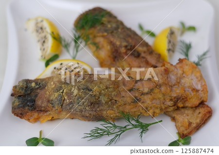 Grilled fish with roasted potatoes and vegetables on plate 125887474