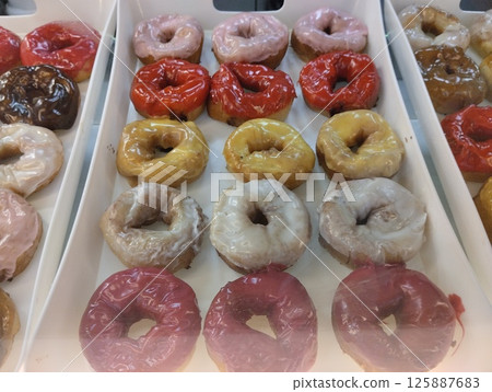 Colored sweet donuts on a tray in a coffee shop bakery. Sweet dishes Colored sweet donuts on a tray in a coffee shop bakery. Sweet dishes 125887683
