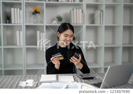 Financial transactions. Happy woman managing bills with credit cards and smartphone. Financial transactions. Happy woman managing bills with credit cards and smartphone. 125887690
