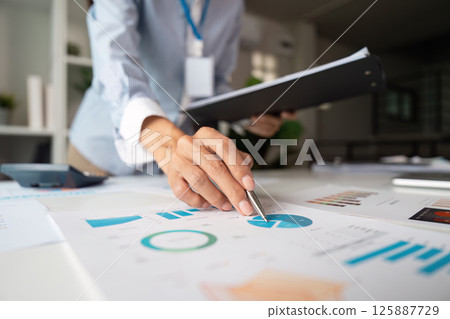 Data Analysis and Presentation. A professional analyzing charts and reports while preparing for a meeting. Data Analysis and Presentation. A professional analyzing charts and reports while preparing for a meeting. 125887729