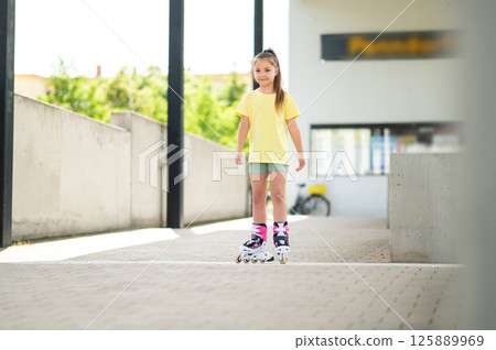 Little girl skating with roller-skates enjoying fun outdoor activity Little girl skating with roller-skates enjoying fun outdoor activity 125889969