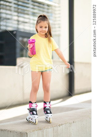 Little girl skating with roller-skates enjoying fun outdoor activity Little girl skating with roller-skates enjoying fun outdoor activity 125889972